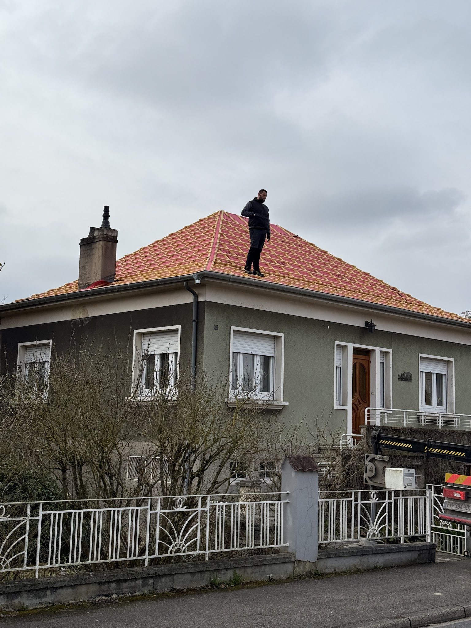 Un couvreur debout sur le faîtage d'une toiture en cours de réfection